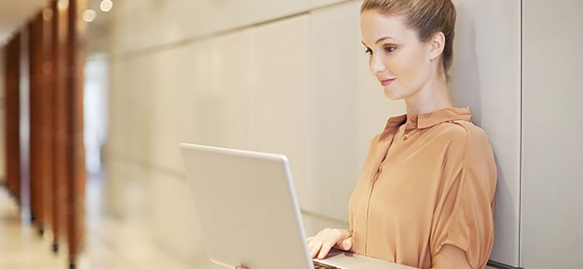 Businesswoman using laptop in corridor