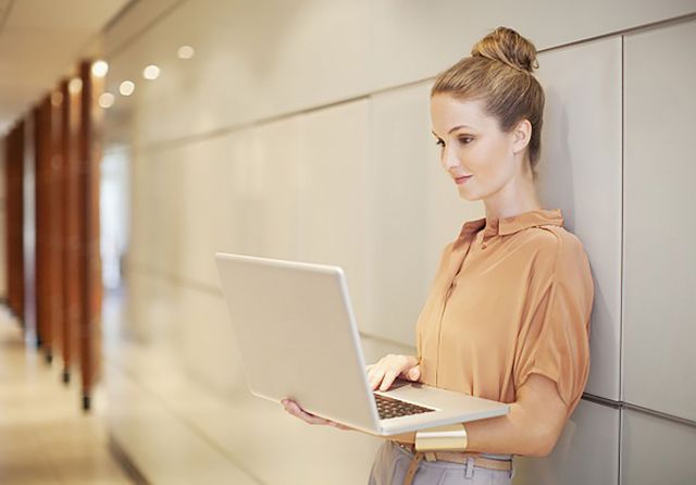 Businesswoman using laptop in corridor