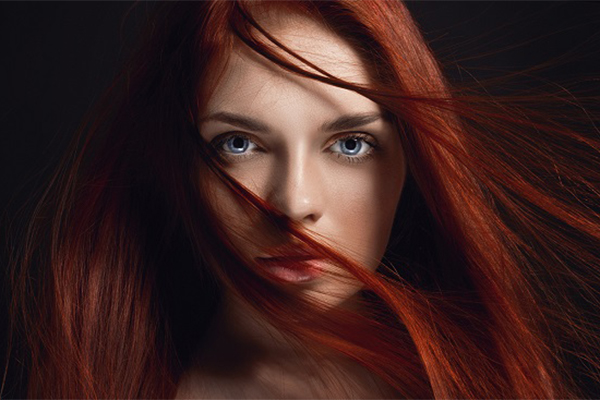 Sexy beautiful redhead girl with long hair. Perfect woman portrait on black background. Gorgeous hair and deep eyes. Natural beauty, clean skin, facial care and hair. Strong and thick hair. Flower